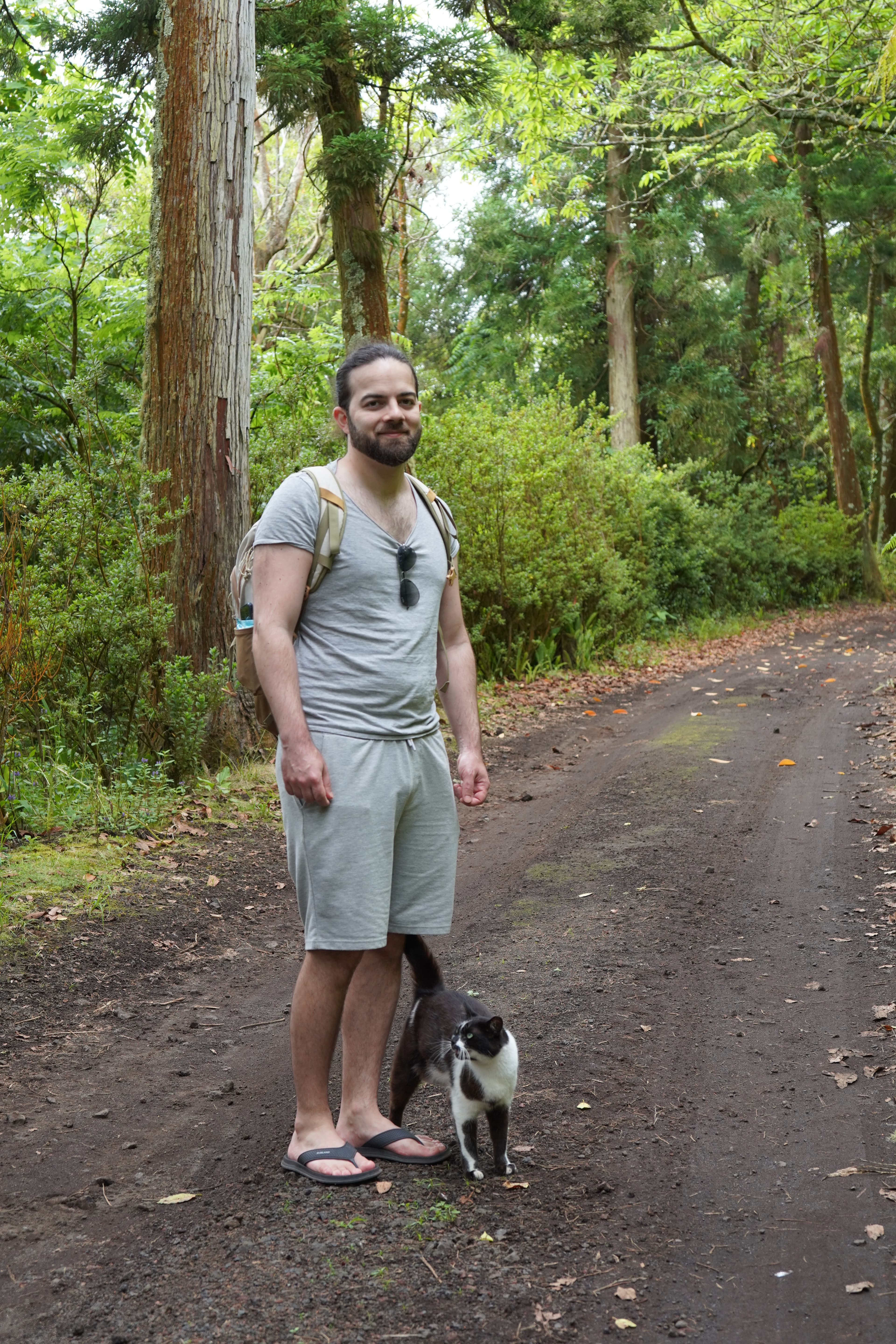 Metin Çelik standing in a forest with a cat